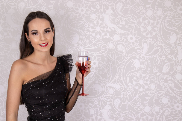 Сексуальная элегантная привлекательная стройная женщина в маленьком черном платье и чулках с бокалом вина, готовая к вечеринке, свадьбе или событию - Фото, изображение