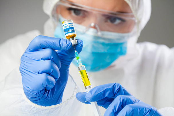 Медицинский ученый держит образец коронавируса COVID-19 вакцины, инъекции желтой жидкости со шприцем джеб, глобальный пандемический кризис, лечение и лечение исследований, испытания добровольцев пациентов, анализ исследований надежда - Фото, изображение