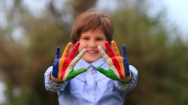 Veselá holčička ukazuje pozdrav gestem s rukama namalovanýma v duhových barvách. Zaměření na ruce - Záběry, video