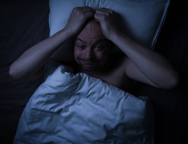 Homme couché au lit, stressé, inquiet et ne peut pas dormir en regardant le plafond. . Photo de haute qualité - Photo, image