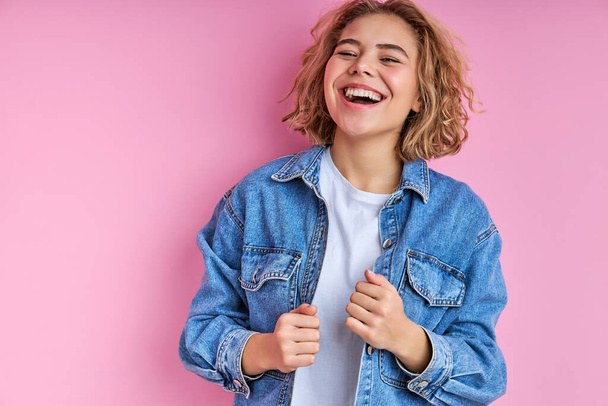 stylish pretty woman in denim jacket laughing on pink background - 写真・画像