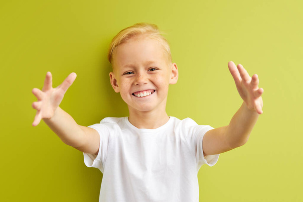 portrait of pretty little caucasian boy with freckles spreading hands, trying to hug friend in school - Φωτογραφία, εικόνα