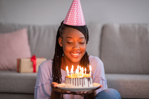 Щаслива африканська жінка, що тримає святковий торт зі свічками
 - Фото, зображення
