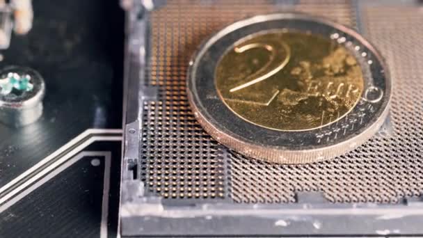 Moneda de 2 euros sobre una ranura para CPU en una placa base, que simboliza el euro digital. - Metraje, vídeo