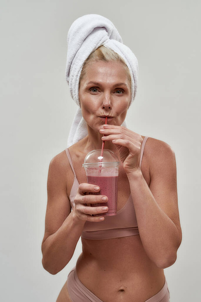 Cheerful middle aged woman in lingerie drinking smoothie - Foto, Imagen