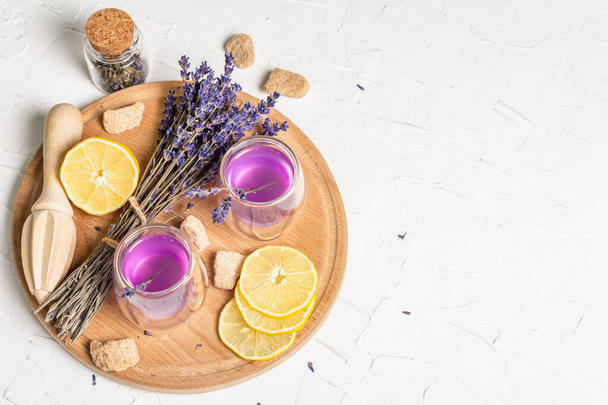 Lemonade with lemons and lavender. A refreshing low alcoholic drink with fresh fruits and a dry bouquet. White putty background, top view - Φωτογραφία, εικόνα