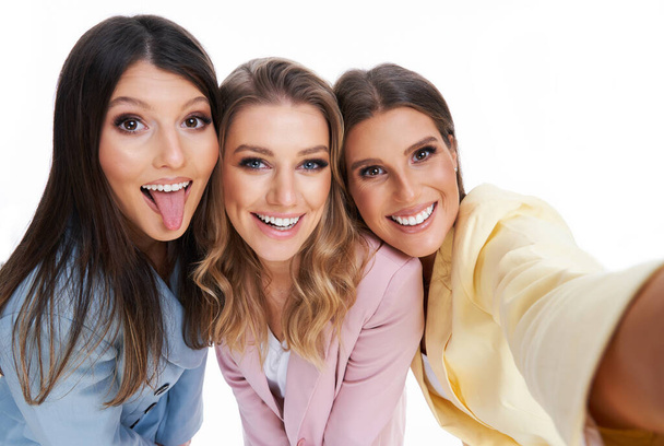 Three women in pastel suits posing over white background - Foto, afbeelding