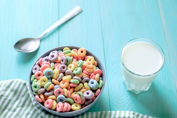Cereali rotondi colorati e un bicchiere di latte su fondo turchese. Preparo la colazione. Foto di alta qualità - Foto, immagini