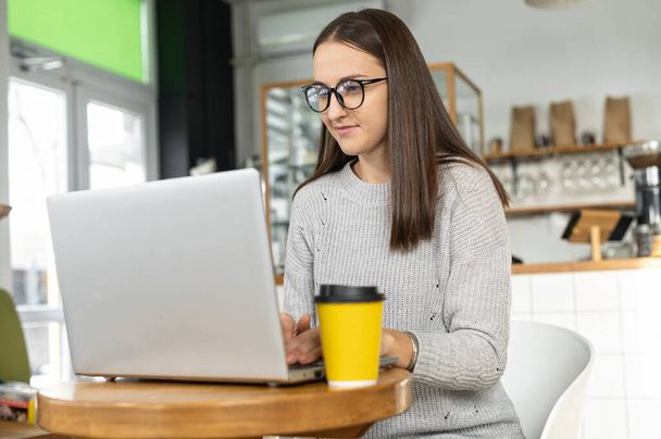 Jonge vrouw met een laptop in het café - Foto, afbeelding