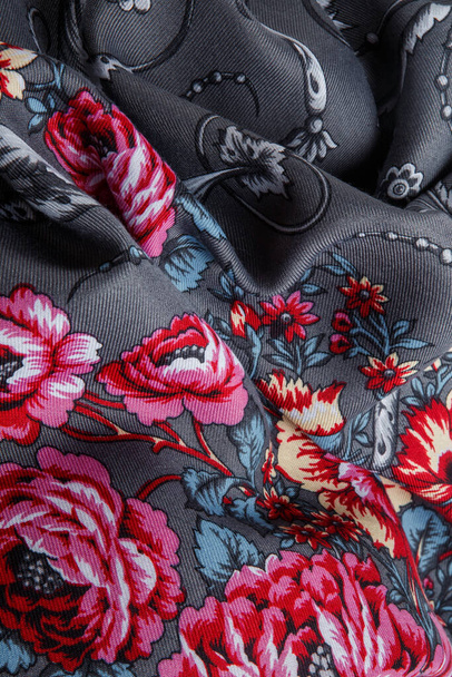 primo piano vista sulla sciarpa femminile in cotone grigio scuro accartocciato con ornamento floreale luminoso con grandi rose rosa - Foto, immagini