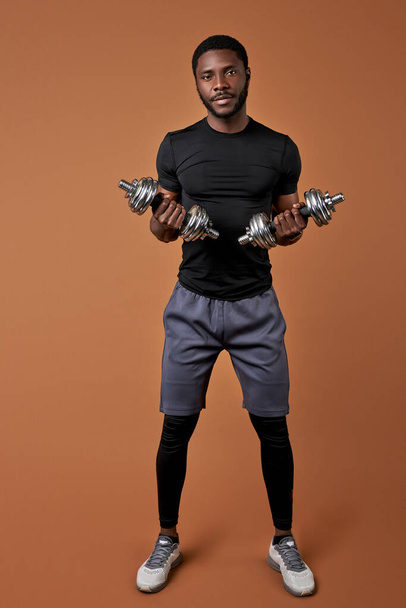 handsome muscular afro man bodybuilder raising dumbbells - Fotografie, Obrázek
