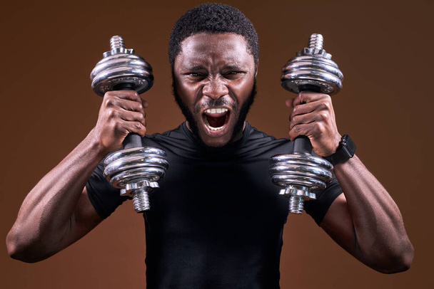 bearded afro american man is trying to lift two large dumbbells at once, screaming - Fotoğraf, Görsel