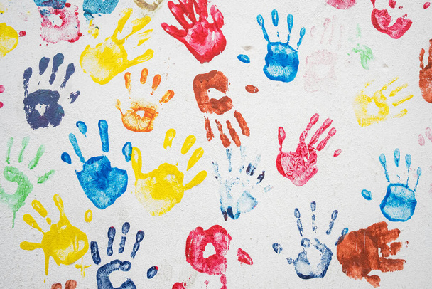 White wall with colorful multicolored hand prints. - 写真・画像