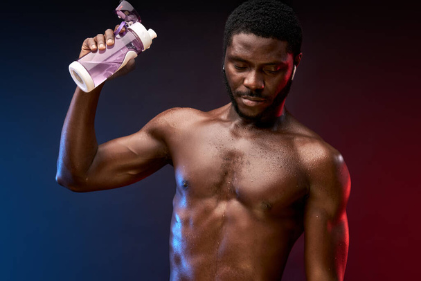 sweaty shirtless sportsman pours water on himself after training - Photo, Image