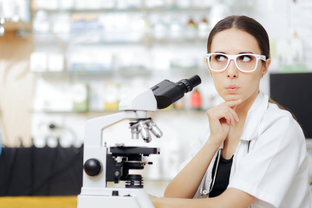 Female Scientist Looking through a Microscope in a Laboratory - Photo, image