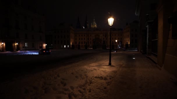 Γκρο πλαν φωτεινό φωτισμένο φανάρι. Λάμπει φανάρι στα φώτα του δρόμου τη νύχτα. Στο βάθος του πεζοδρομίου περπατά σιλουέτες των ανθρώπων που πέφτουν χιόνι το χειμώνα - Πλάνα, βίντεο