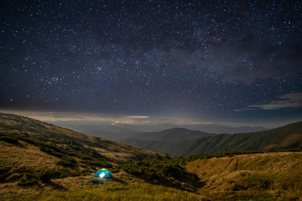 山の星空を背景にテントを張る - 写真・画像