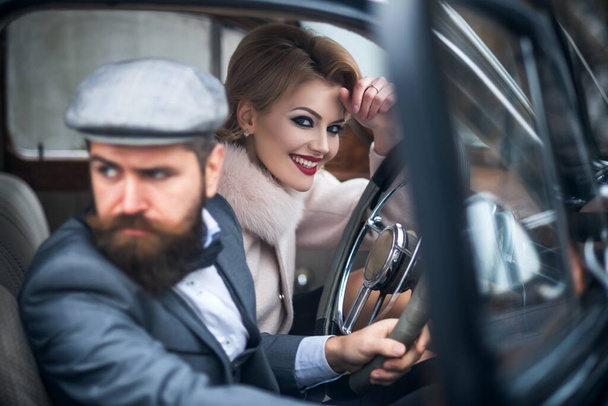 The couple in retro car. Young people together while sitting inside a vintage car. - Foto, imagen