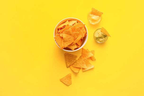 Bowl ízletes nachos és mártások színes háttér - Fotó, kép
