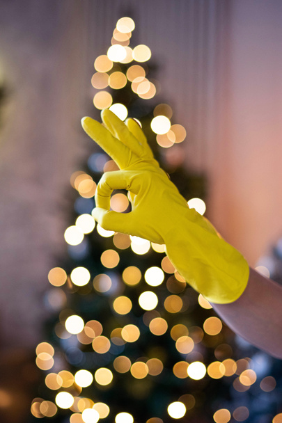 Een hand in een gele rubberen handschoen. Algemene professionele schoonmaak voor Kerstmis. Goed teken.. - Foto, afbeelding