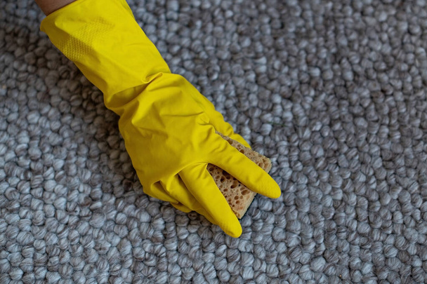 Una chica con guantes de goma amarilla limpia la alfombra con una esponja. Limpieza profesional de casas. Limpieza en seco de la alfombra - Foto, Imagen