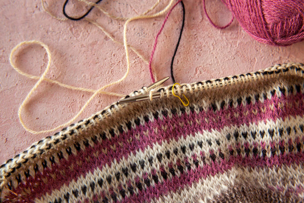 fragment van warm gestreepte raglan trui op roze betonnen achtergrond. - Foto, afbeelding