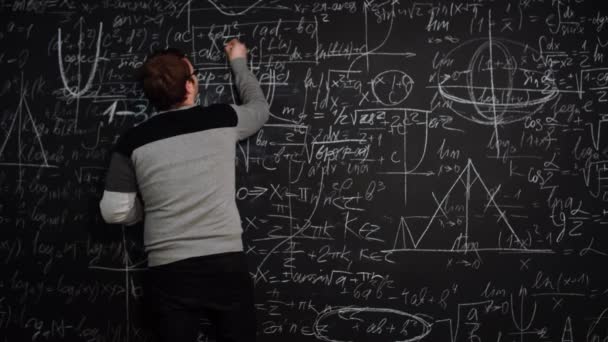 L'uomo scrive la formula sulla lavagna piena di equazioni algebriche e sorrisi incrociati - Filmati, video