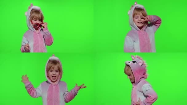 Ребенок в пижаме единорога делает глупые смешные лица, валяет дурака, показывает язык на хроме ключа - Кадры, видео