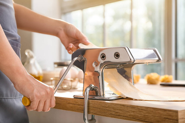 Mujer haciendo pasta con máquina en la mesa en la cocina - Foto, Imagen