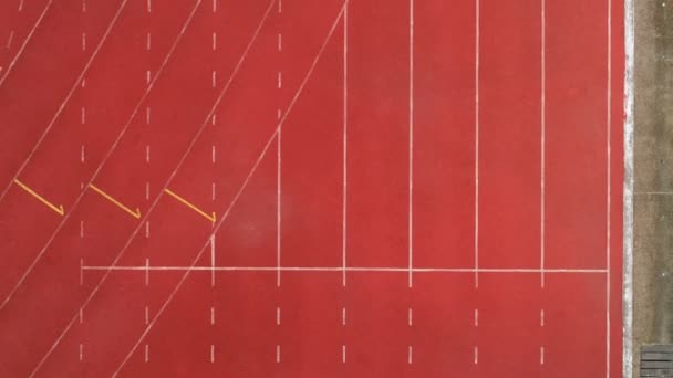 Tor wyścigowy lub lekkoatletyka linia startowa z numerami pasa ruchu na stadionie Top view Drone shot high angle view - Materiał filmowy, wideo