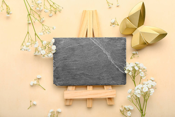 Empty chalkboard with spring flowers and figurine of butterfly on color background - Foto, afbeelding