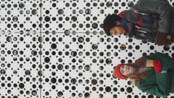 Senkrecht nach oben gedrehte Aufnahme von jungen multiethnischen Männern und Frauen in Oberbekleidung, die Kaffeetassen halten, miteinander reden und dann gemeinsam für die Kamera im Freien in der Stadt posieren - Filmmaterial, Video