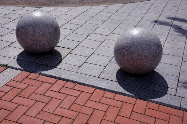 Twee decoratieve granieten bollen op de stoep in de straat - Foto, afbeelding