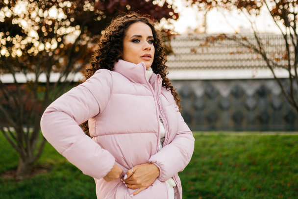 something looking in the pocket of a down jacket curly brunette in the park - Zdjęcie, obraz