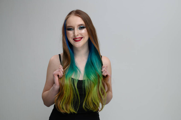 Photo portrait of a caucasian girl with long dyed hair smiling on a white background - Foto, afbeelding