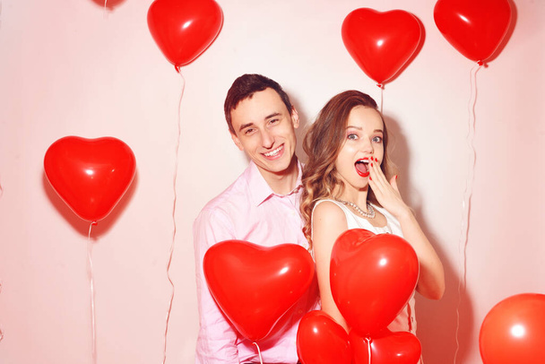 Sevimli sevgilisiyle dans eden ve Sevgililer Günü 'nde eğlenen bir adam. Sevgililer günü partisi. Arka plan kırmızı balonlar kalpler. Aşk konsepti. Çılgın.  - Fotoğraf, Görsel