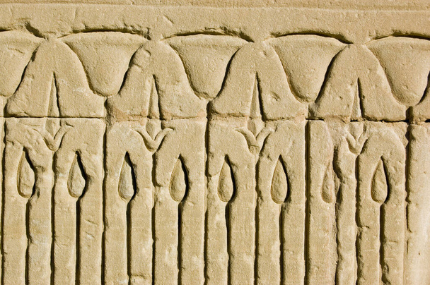 Kadim bir Mısır taşının yakın çekiminde kamış yatağına nilüfer çiçekleri oyulmuş. Horus Tapınağının dış duvarı, Edfu, Mısır. - Fotoğraf, Görsel
