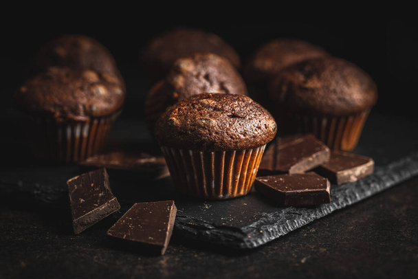Chocolate muffins. Sweet dark cupcakes on black table. - Fotó, kép