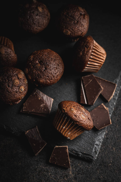 Chocolate muffins. Sweet dark cupcakes on black table. - Fotoğraf, Görsel