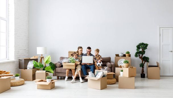 Obsah rodiny sedí společně na pohovce v novém bytě s vybalenými boxy a pomocí notebooku při přestávce během stěhování - Fotografie, Obrázek