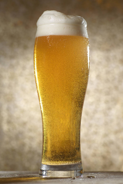 Cerveza. Jet de cerveza se vierte en un vaso de cerveza, causando una gran cantidad de burbujas y espuma - Foto, imagen