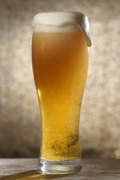 De la bière. Jet de bière est versé dans un verre de bière, causant beaucoup de bulles et de mousse - Photo, image