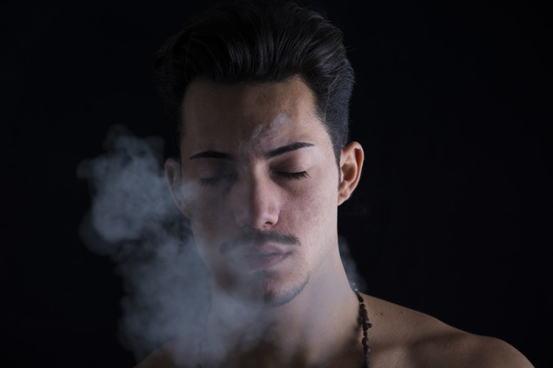 Attractive young man smoking, eyes closed - Foto, afbeelding