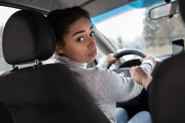 Елегантна жінка-водій дивиться на заднє сидіння, запитуючи ремінь безпеки пасажирів
 - Фото, зображення