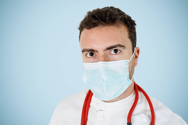 Porträt eines männlichen Arztes mit Gesichtsmaske im Hintergrund - Foto, Bild