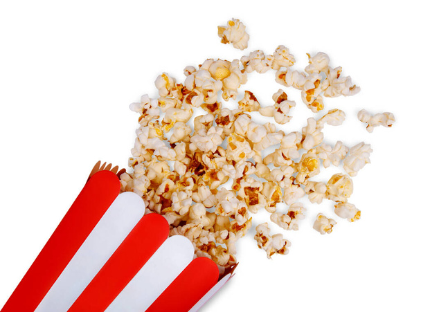 Finom popcorn és felborult piros csíkos papír popcorn vödör elszigetelt fehér alapon. - Fotó, kép