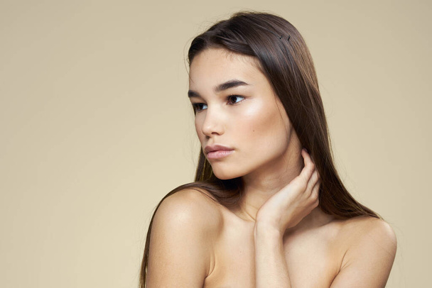 Jolie femme épaules nues cosmétiques peau propre soins des cheveux fond beige - Photo, image