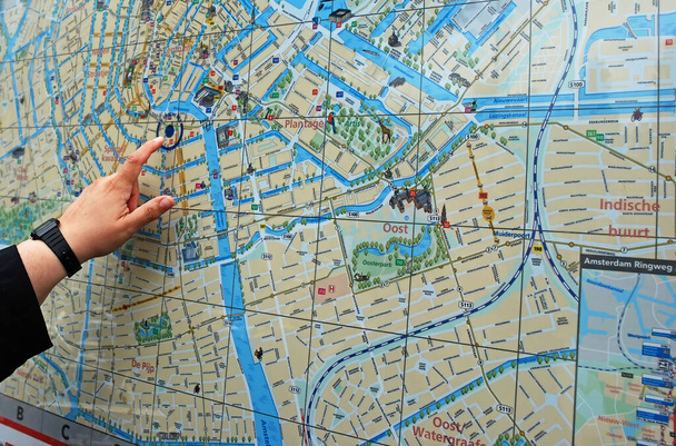Female finger pointing to a point on the public map of Amsterdam. - Фото, изображение