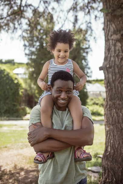 Afroamerikaner verbringt Zeit mit seiner Tochter im Park und sieht fröhlich aus - Foto, Bild