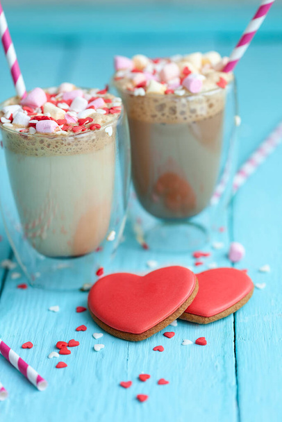 Two glasses of hot coffee or cappuccino with marshmallows and heart-shaped cookies on a light blue wood background. Holiday Valentine's Day. - Foto, Imagem